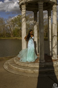 a woman in a blue dress is posing in front of a gazebo